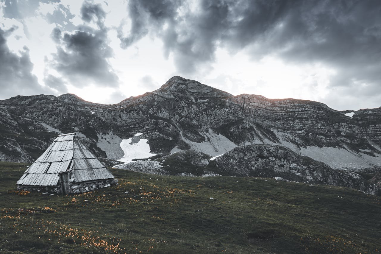 Captivating view of a rustic wooden hut set against the dramatic mountains of Opština Kolašin, Montenegro.