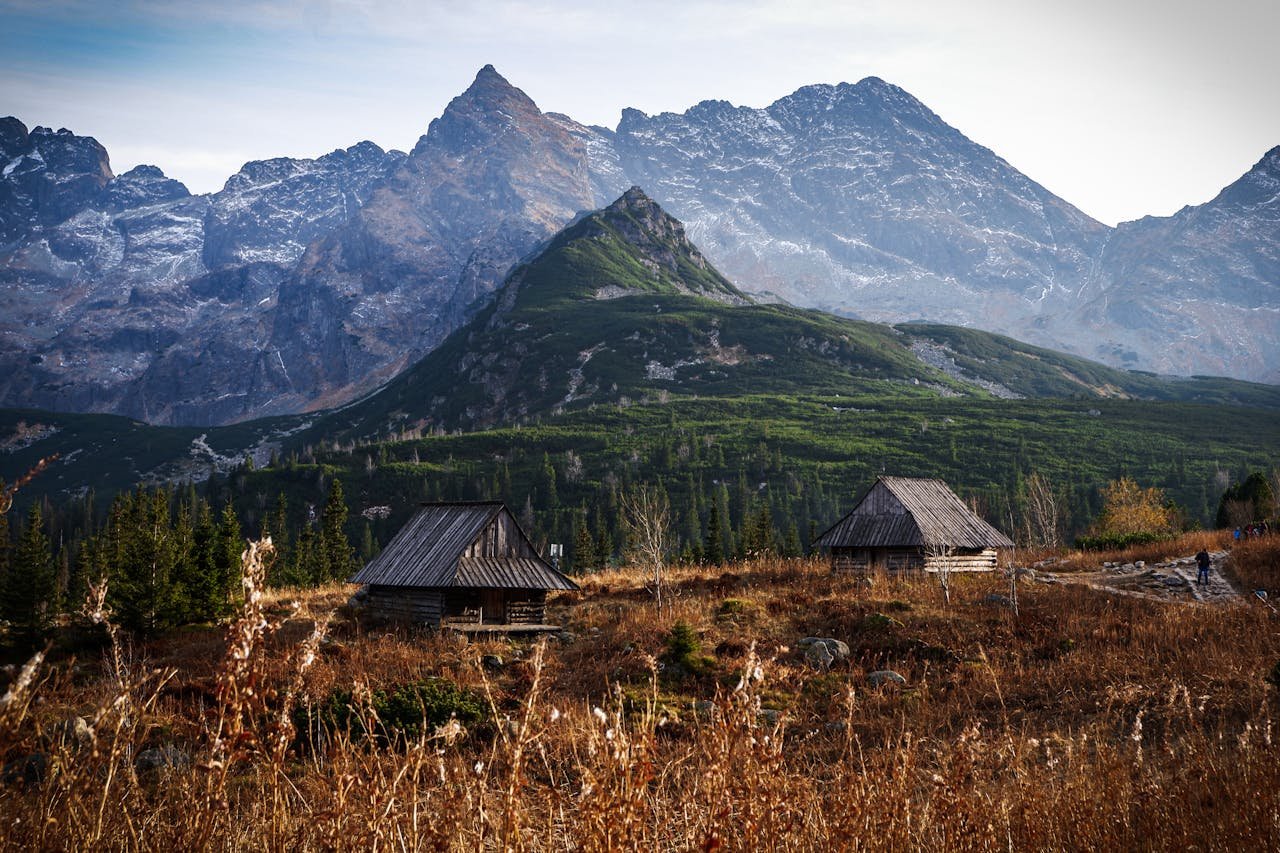 A stunning mountain landscape with wooden huts set against a majestic backdrop.