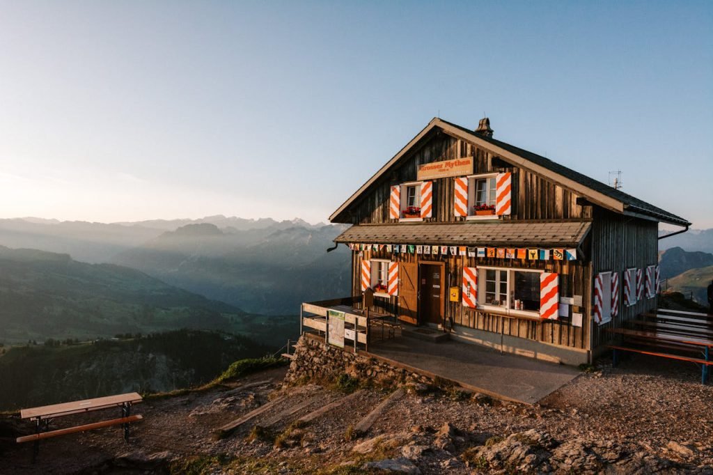 Capture the serene beauty of a Swiss mountain cabin at sunrise in Schwyz.